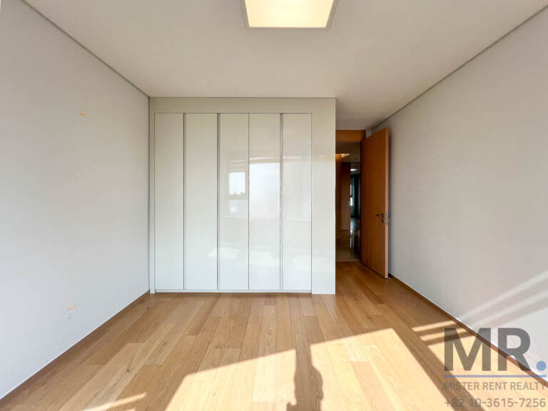 Master bedroom with white built-in wardrobe and oak floor