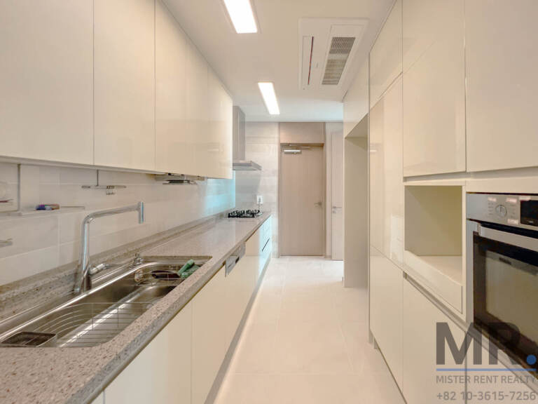 Galley kitchen with white cabinets, granite counter and built-in oven