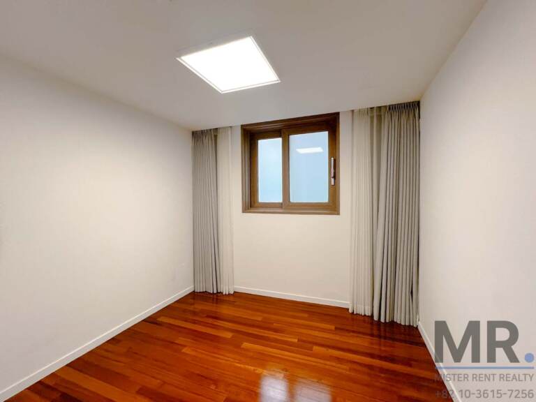 Small bedroom with hardwood floors and curtained window