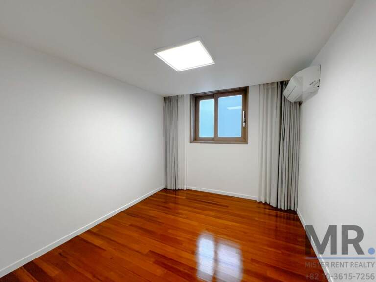 Bedroom with wood-framed window and gray curtains