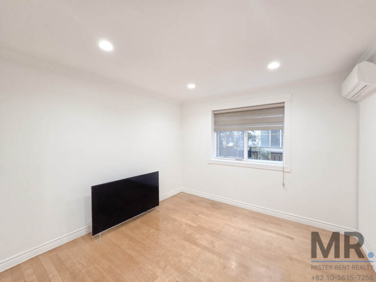 Bedroom with wall air conditioner and window with roller blind