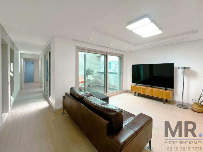 Living room with brown leather sofa and sliding doors to the terrace