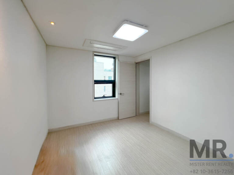 Empty bedroom with tall window and light wood floor