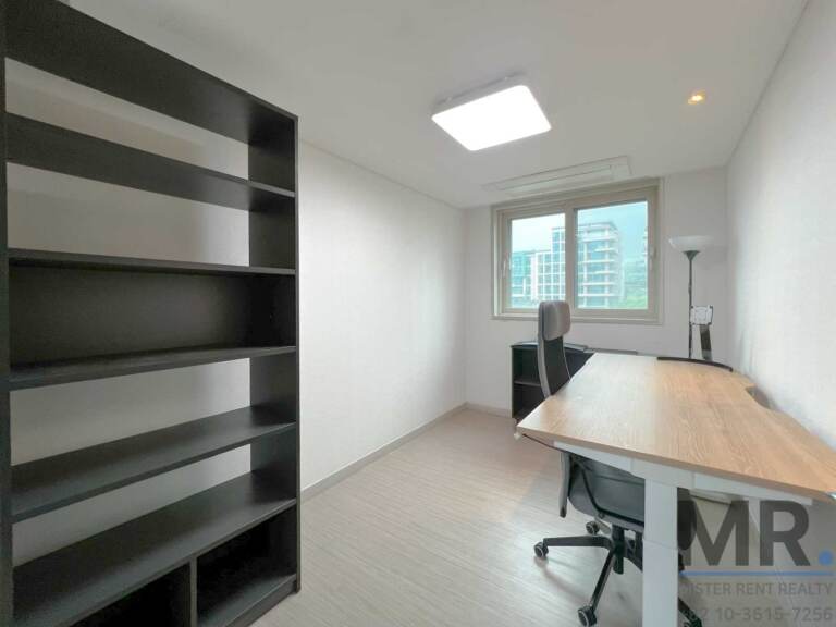 Study with tall black bookshelf, wooden desk and office chair
