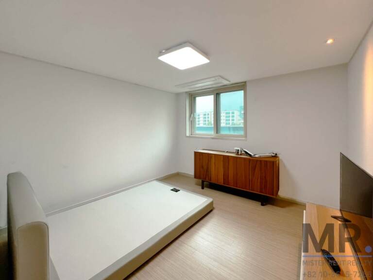 Bedroom with low bed frame, walnut sideboard and window