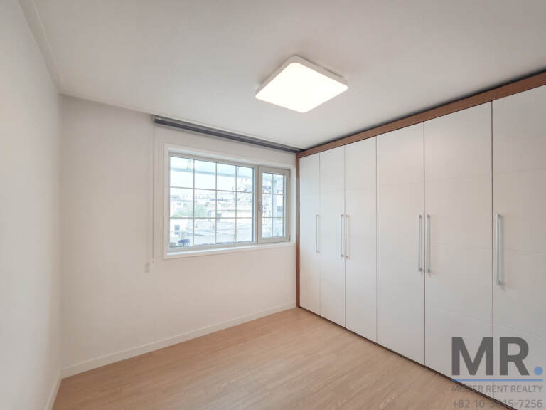 Bedroom with wall-length white wardrobe and window