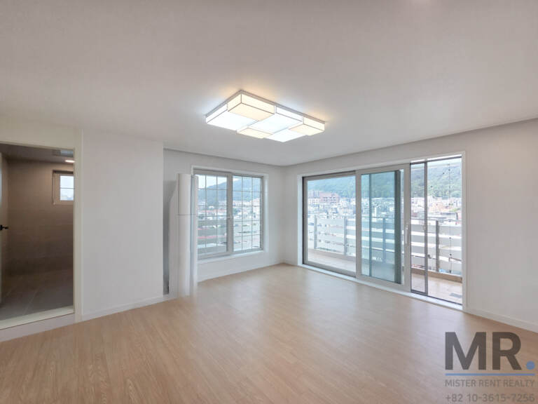 Living room with modern ceiling light and balcony overlooking hillside houses
