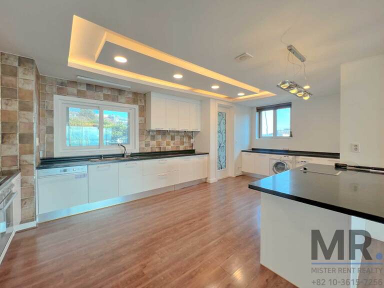 Kitchen with island, white cabinets and window over the sink