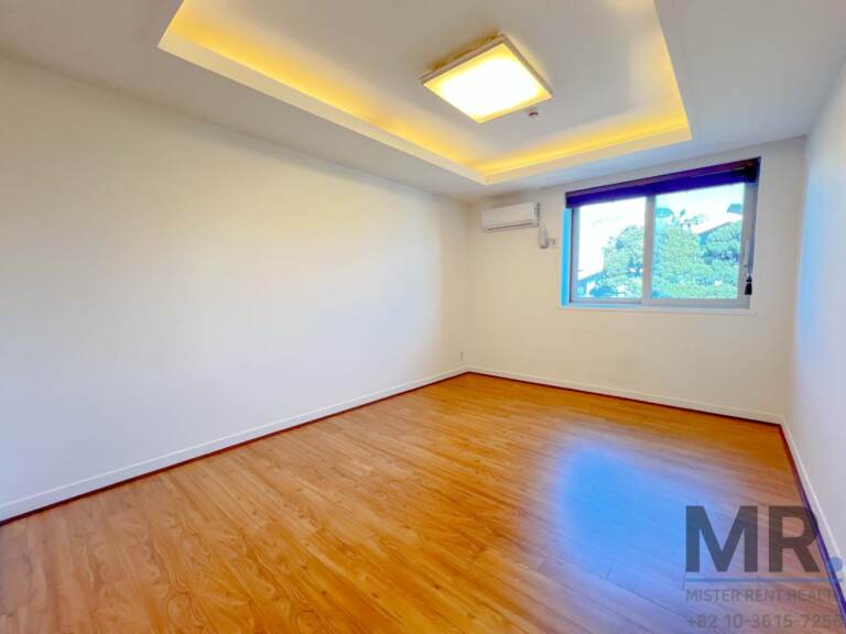 Long bedroom with cove lighting and tree-view window