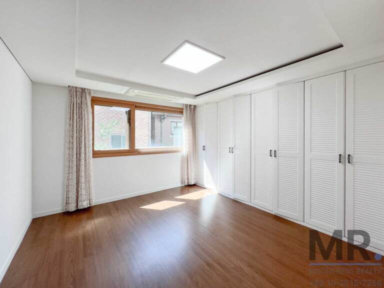Master bedroom with louvered white wardrobes and patterned curtains
