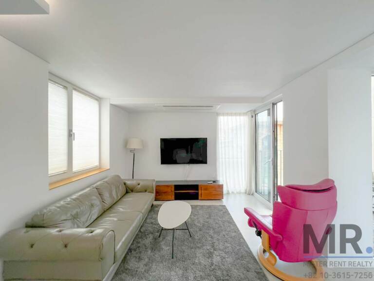 Living room with leather sofa, pink lounge chair and wall-mounted TV