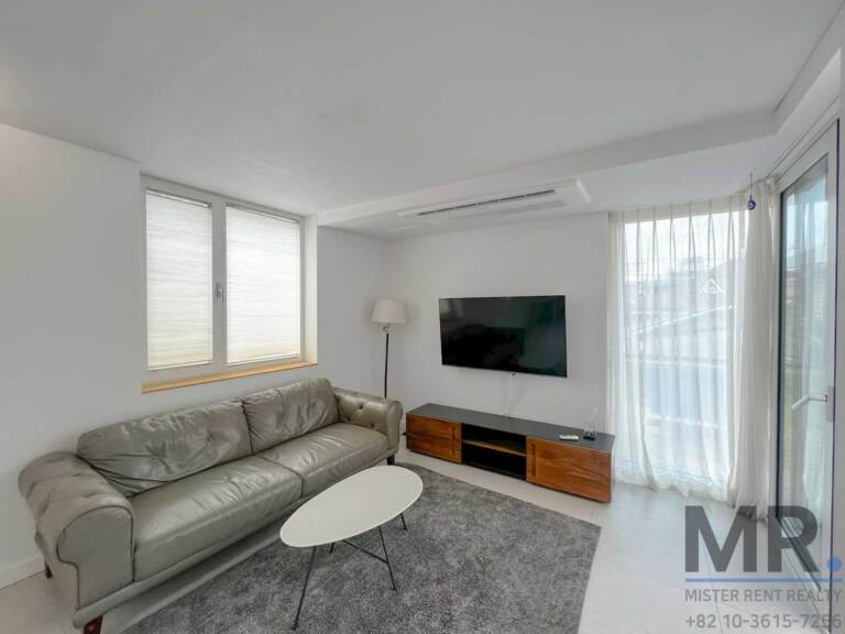 TV lounge with gray leather sofa and sheer curtains