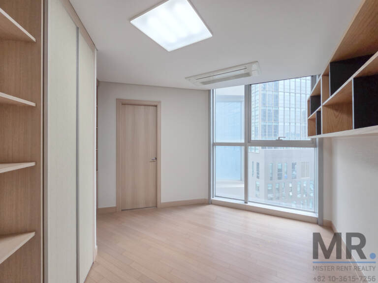Bedroom with built-in shelving and wardrobe beside tall windows