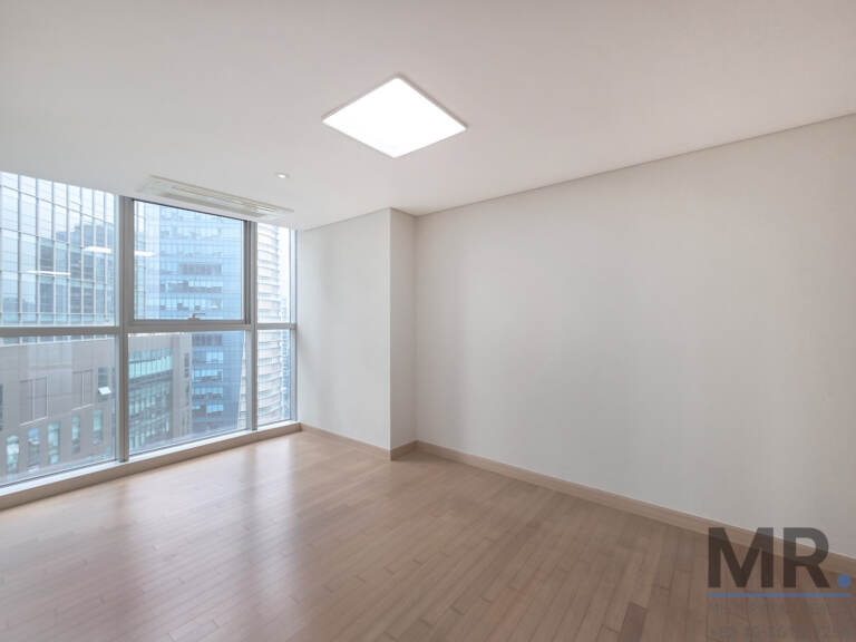 Empty bedroom with corner windows facing office towers