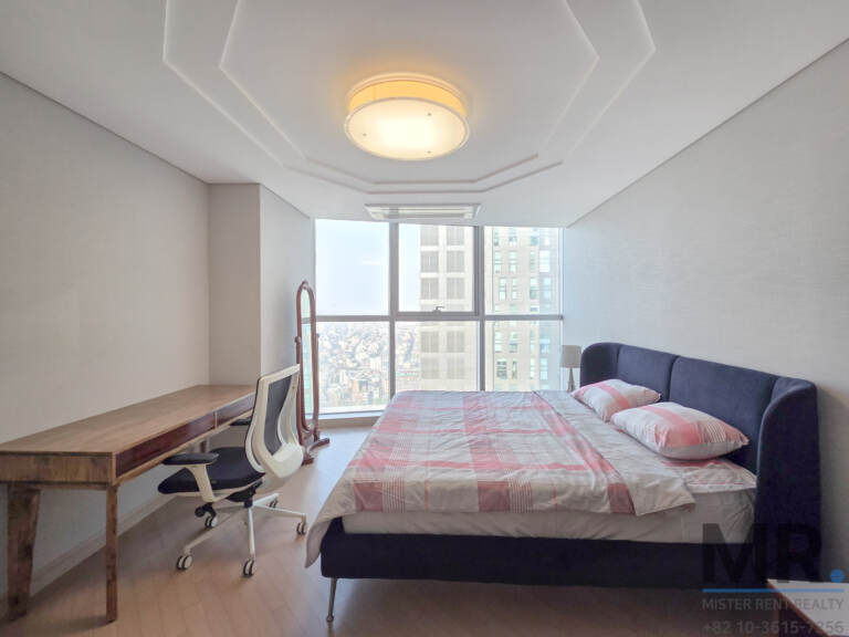 Bedroom with navy headboard bed, wooden desk and office chair