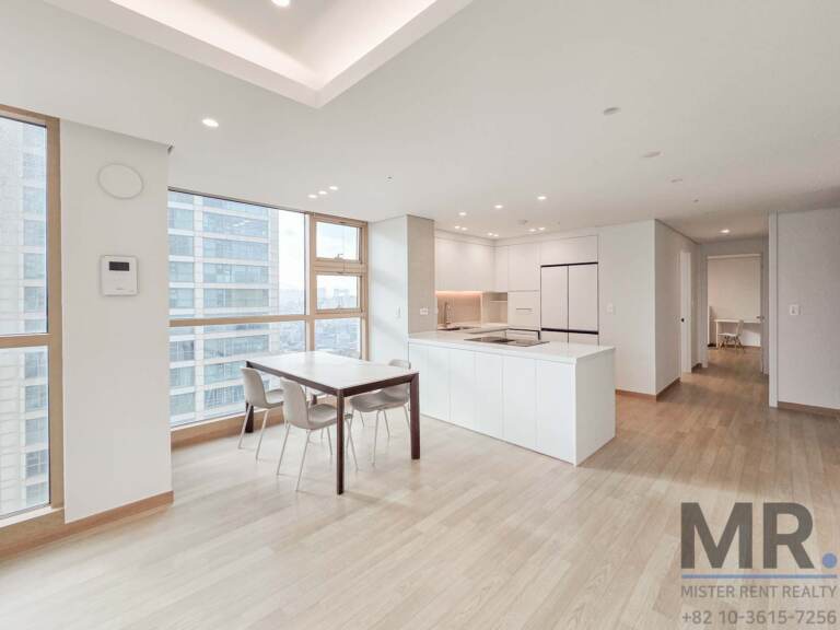 Open dining area with kitchen island and window toward apartment towers