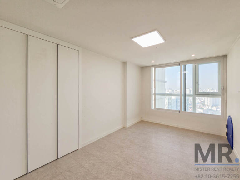 Bedroom with full-height sliding wardrobe and city-view window