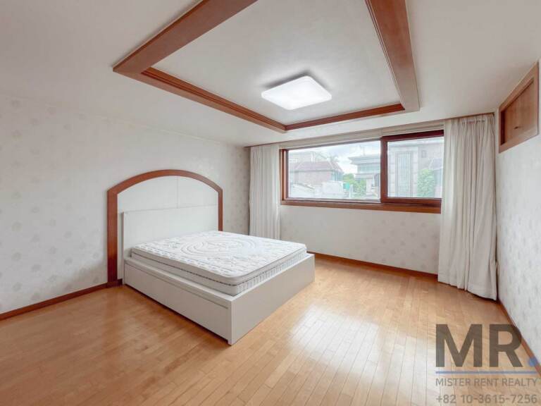 Bedroom with white bed, tray ceiling and curtained window