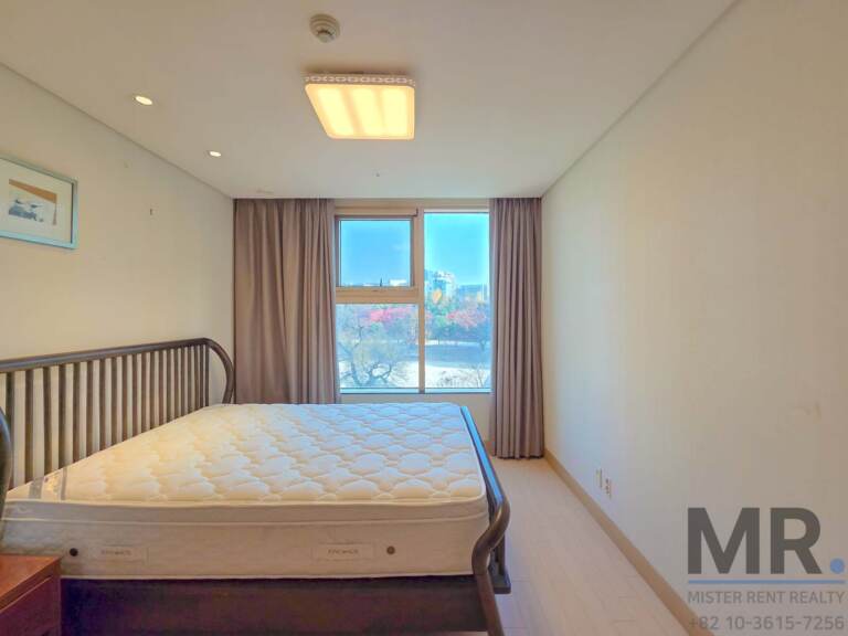 Bedroom with double bed and window overlooking autumn trees