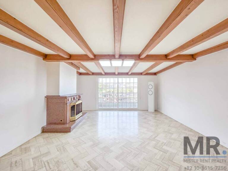 Living room with wooden beam ceiling, stone fireplace and gridded window