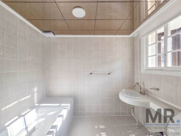 Bathroom with bathtub, beige tiles and window above the sink
