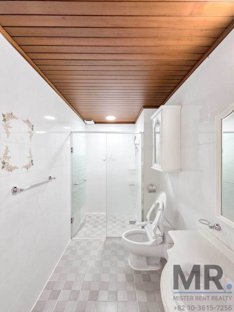 Bathroom with glass shower, bidet toilet and wood-paneled ceiling