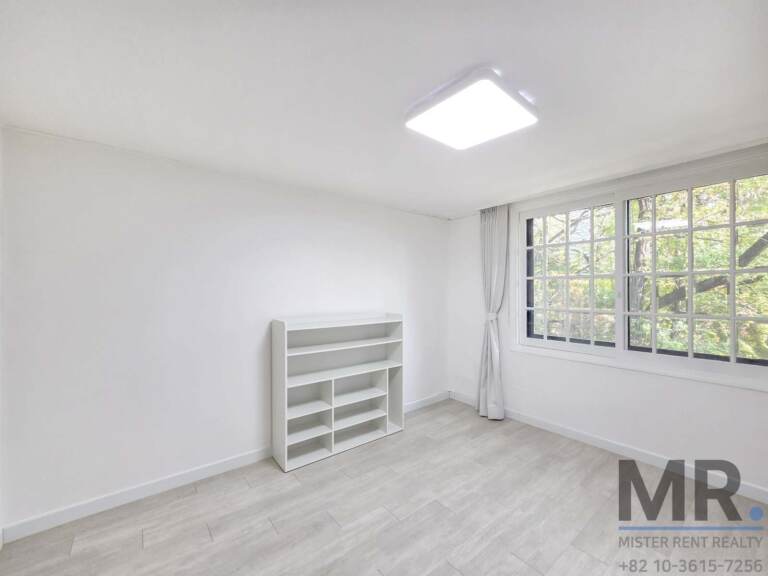 Bedroom with white shelving unit and windows overlooking pine trees