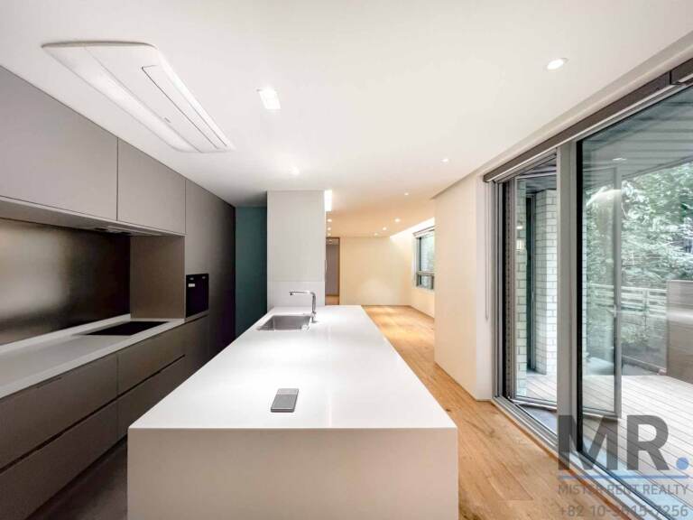 Open kitchen with long white island and grey built-in cabinets