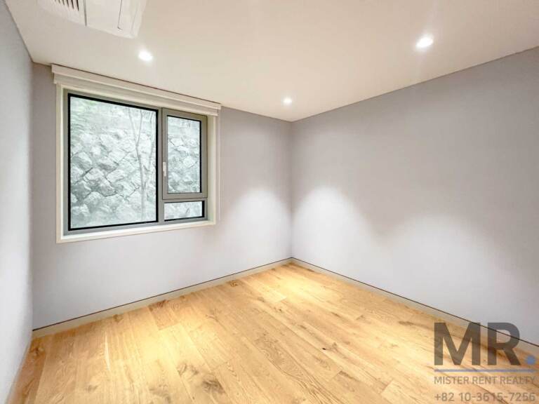 Small bedroom with grey walls and window to a stone wall